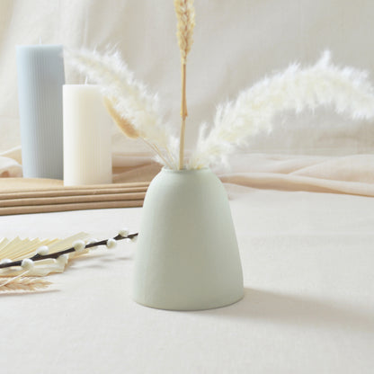 The back of a handmade, pastel mint, short rim vase with a gold heart.