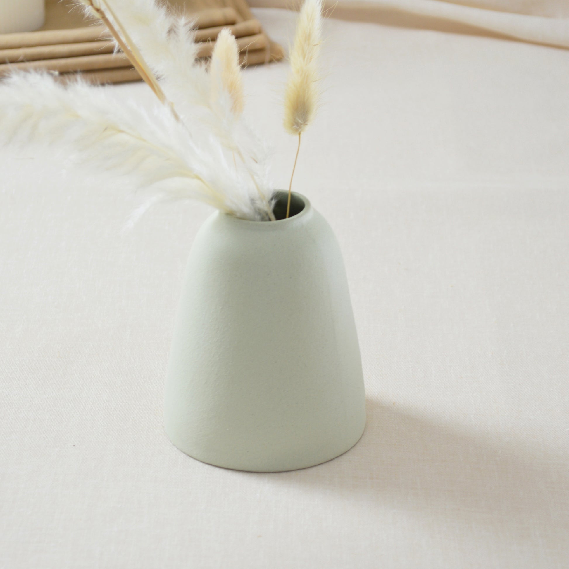 The back of a handmade, pastel mint, short rim vase with a gold heart.